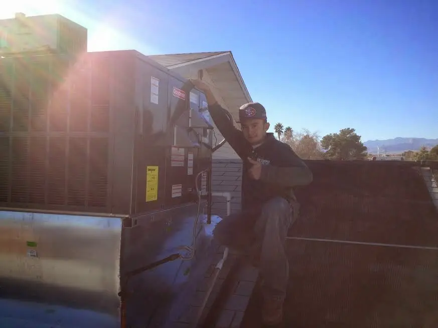 HVAC technician performing AC Tune-Up on a rooftop unit in Redford